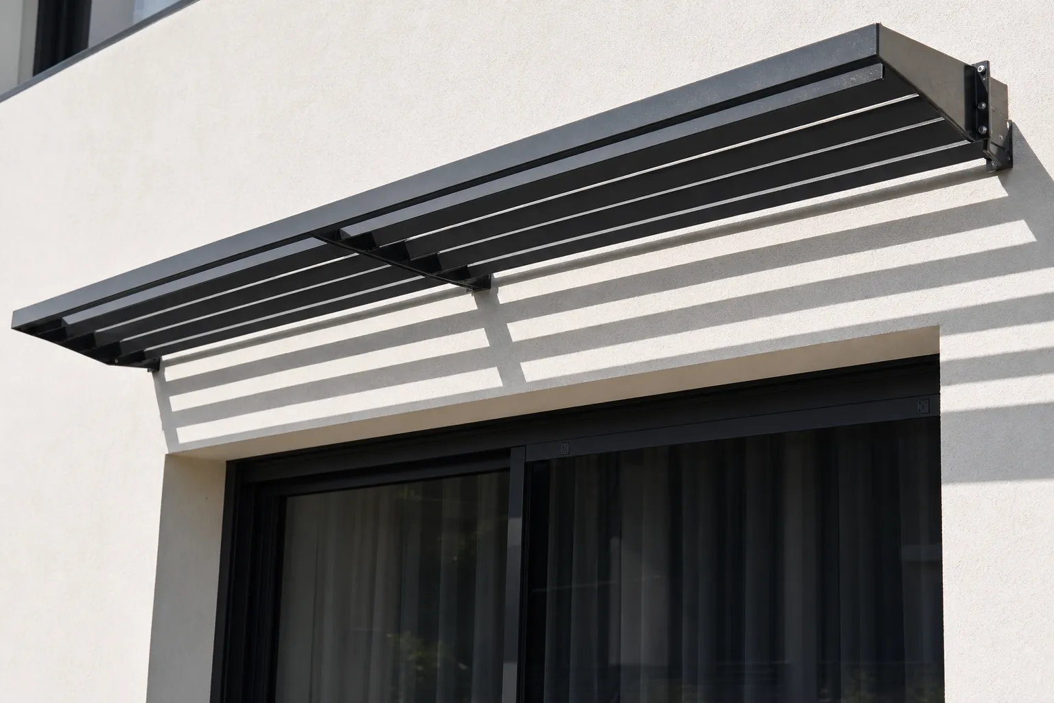 Brise-soleil orientable en aluminium fixé en façade au-dessus d’une baie vitrée