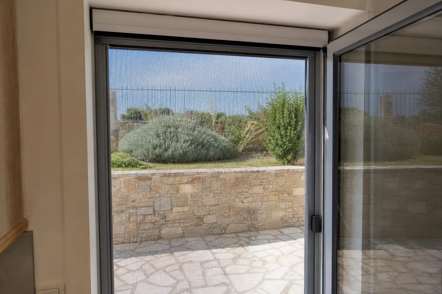 Moustiquaire enroulable sur mesure installée sur une porte-fenêtre ouverte